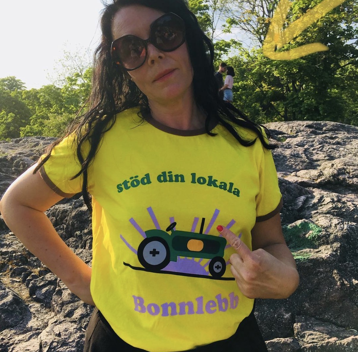 Person i gul t-shirt med traktortryck som pekar på trycket